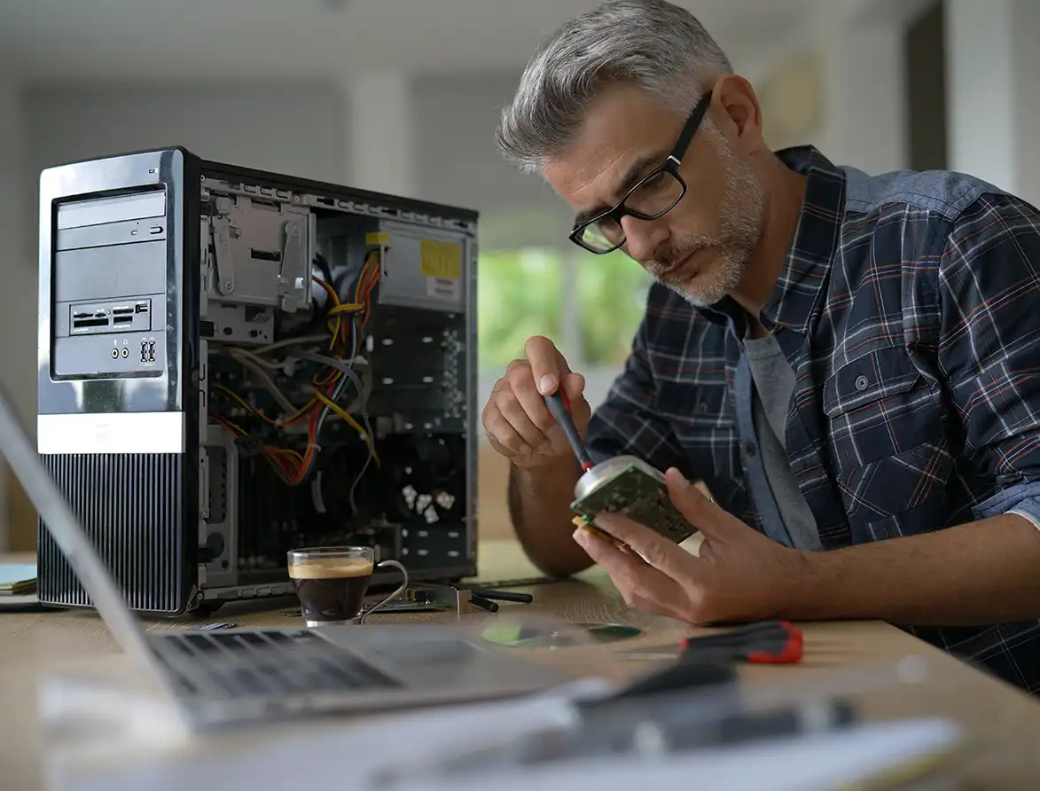 Ein Mann mit Brille und grauem Haar arbeitet präzise an einem geöffneten PC-Gehäuse. Er demonstriert technisches Know-how und handwerkliches Geschick, ideal für IT-Fachkräfte, Elektroniker und Entwickler.